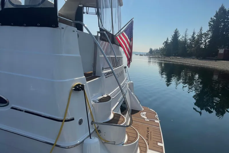 Slide: The Image of 2002 Carver 346 Aft Cabin yacht docked by serene waters, American flag displayed. - 2