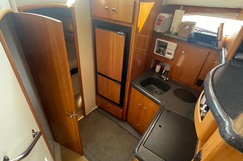 Slide: The Image of 2002 Carver 346 Aft Cabin kitchen with wood cabinetry and compact appliances. - 21