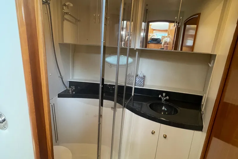 Slide: The Image of 2002 Carver 346 Aft Cabin bathroom with shower, black countertop, and mirrored cabinets. - 36