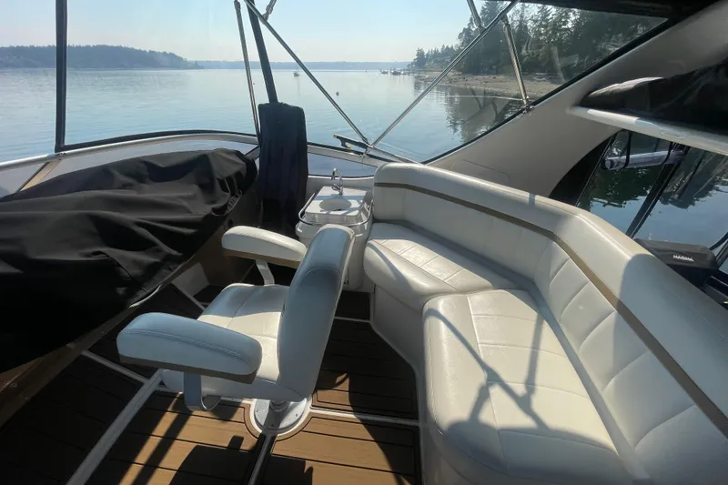Slide: The Image of 2002 Carver 346 Aft Cabin interior with white seating, overlooking serene waters. - 5