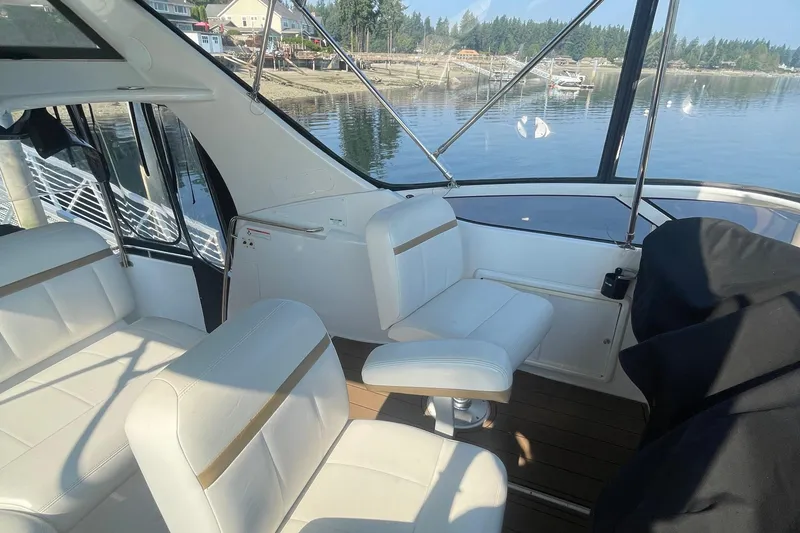 Slide: The Image of Interior of 2002 Carver 346 Aft Cabin yacht with white seating and scenic water view. - 9
