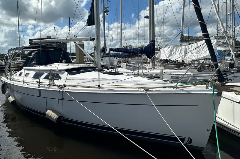 The Image of 2006 Hunter 41 Deck Salon sailboat docked at marina under cloudy sky. - 1