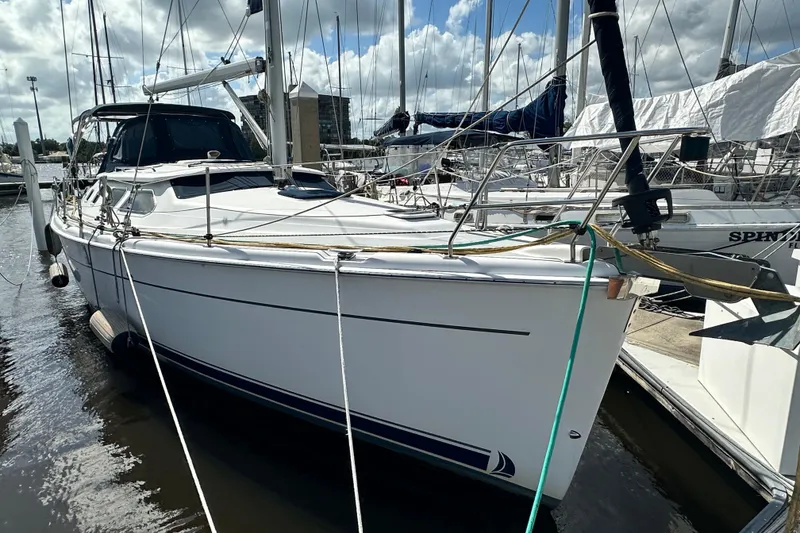 Slide: The Image of 2006 Hunter 41 Deck Salon sailboat docked at marina under cloudy sky. - 2