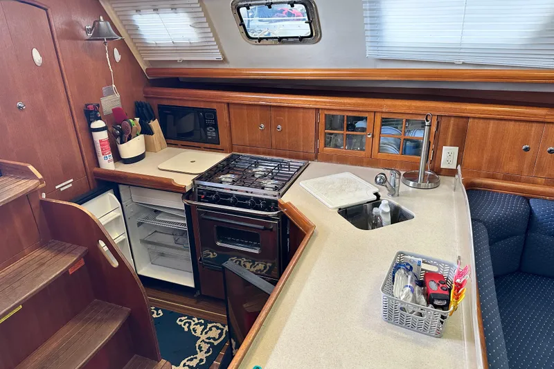 Slide: The Image of 2006 Hunter 41 Deck Salon interior kitchen with stove, sink, and wooden cabinetry. - 34