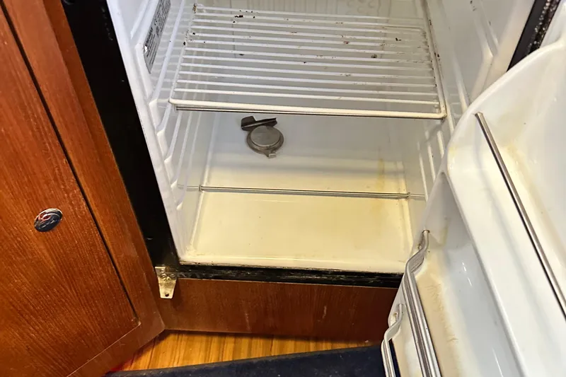 Slide: The Image of Open refrigerator inside 2006 Hunter 41 Deck Salon yacht, showing empty shelves and wooden cabinetry. - 35