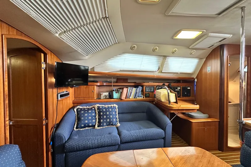 Slide: The Image of Interior of 2006 Hunter 41 Deck Salon with blue sofa, wooden cabinetry, and navigation station. - 49