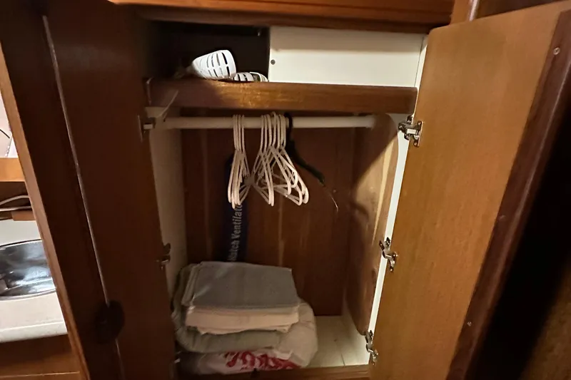 Slide: The Image of Open wooden closet in 2006 Hunter 41 Deck Salon with hangers and folded linens. - 55
