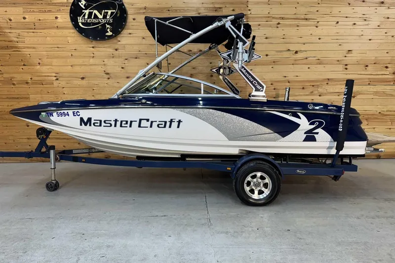 The Image of 2011 MasterCraft X2 boat on trailer in showroom with wooden wall background. - 1