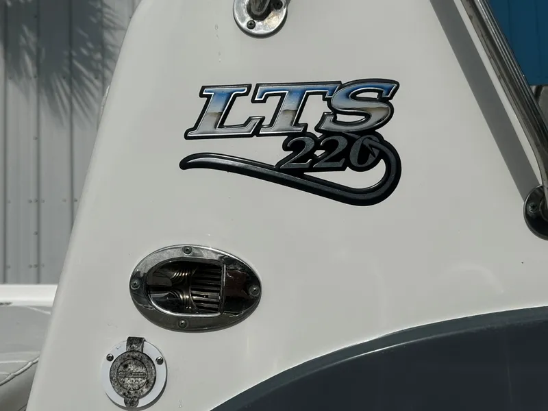 Slide: The Image of Triton 220LTS 2018 boat logo on white surface with chrome details. - 12