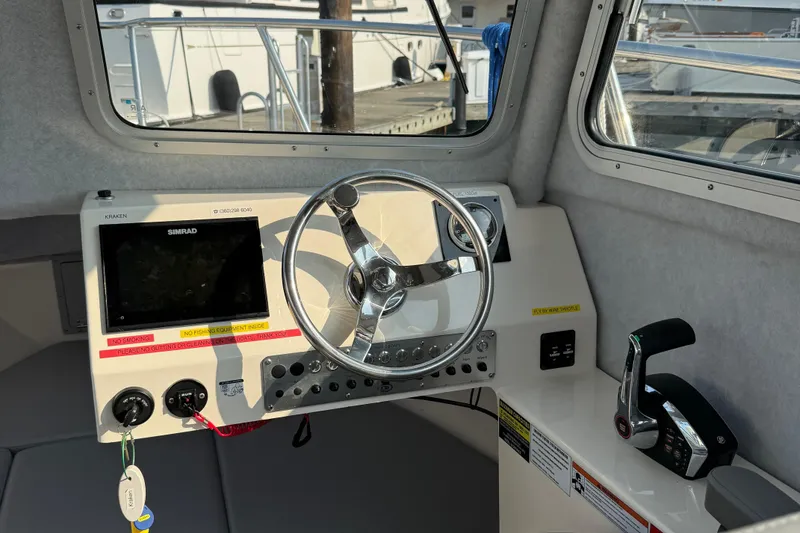 Slide: The Image of 2024 Defiance Admiral 220 EX boat cockpit with steering wheel and control panel. - 2