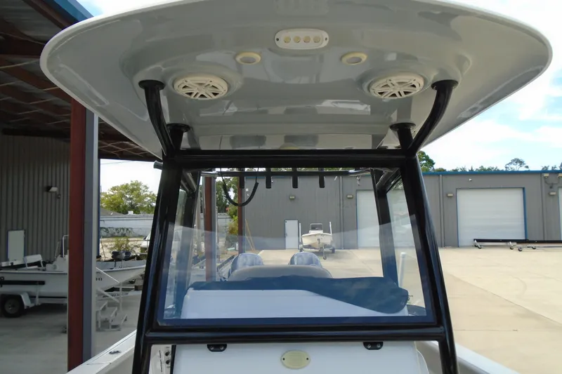Slide: The Image of 2021 Sportsman Open 252 Center Console boat with T-top and speakers in a marina. - 17