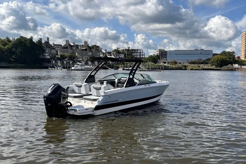 Slide: The Image of 2025 Chaparral 250 OSX boat on a calm river with scenic background. - 2