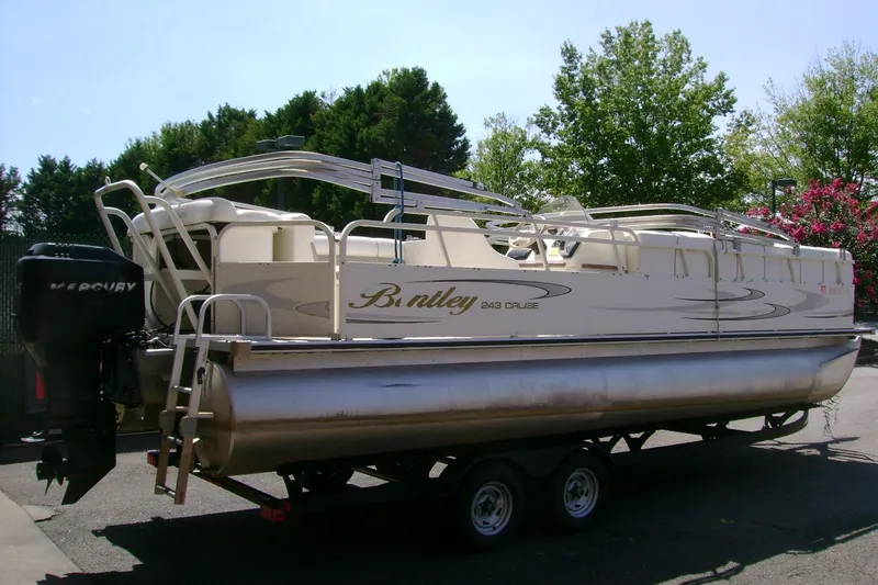 Slide: The Image of 2006 Bentley Pontoons 243 Cruise on trailer, parked outdoors with trees in background. - 1