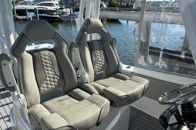 Slide: The Image of 2024 Cape Horn 34 XS boat interior with luxurious seating and steering wheel, docked by the water. - 13