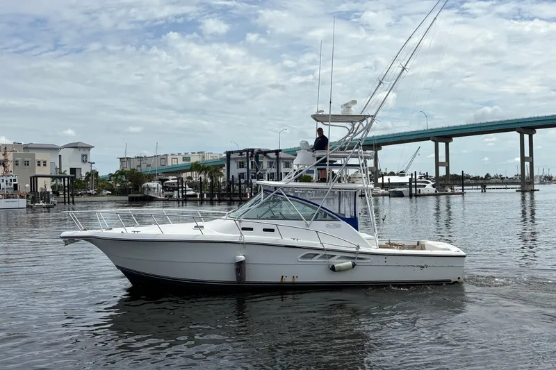 Slide: The Image of 2006 Rampage 38 Express boat cruising near a marina with a bridge in the background. - 2