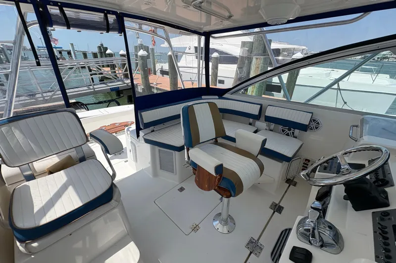 Slide: The Image of 2006 Rampage 38 Express boat interior with seating and steering wheel, docked at marina. - 22