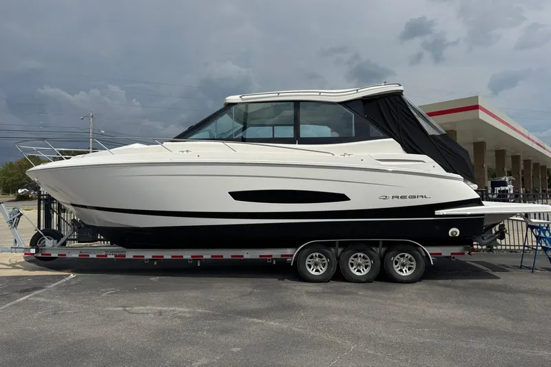 The Image of 2026 Regal 36 Grande Coupe boat on trailer, side view, under cloudy sky. - 0