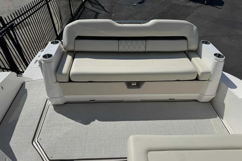 Slide: The Image of 2026 Regal 36 Grande Coupe boat seating area with cup holders and cushioned bench. - 6