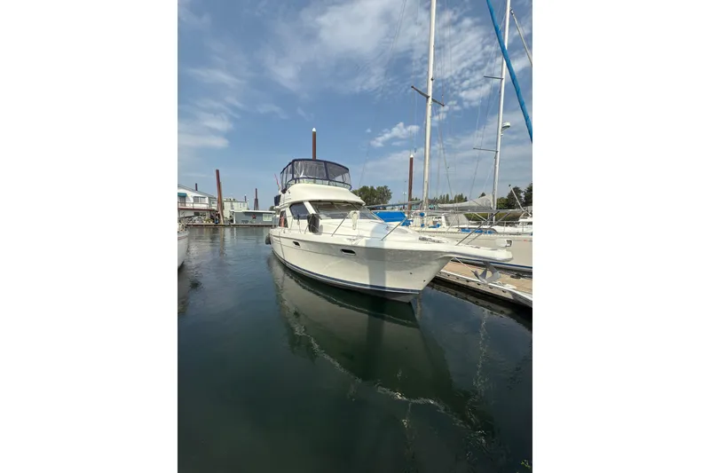 The Image of 1997 Bayliner 3788 Command Bridge Motoryacht docked in a marina under a clear sky. - 1