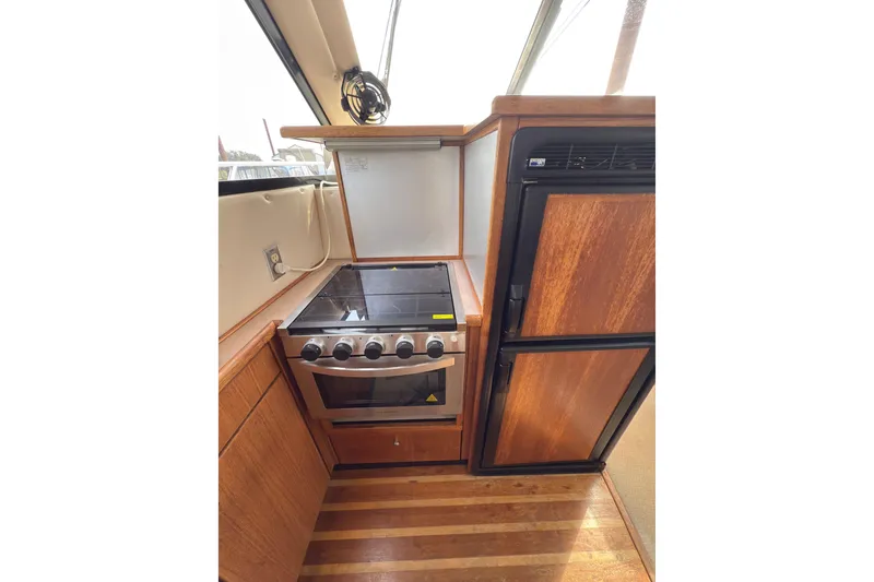 Slide: The Image of 1997 Bayliner 3788 Command Bridge Motoryacht kitchen with stove and wooden cabinetry. - 23