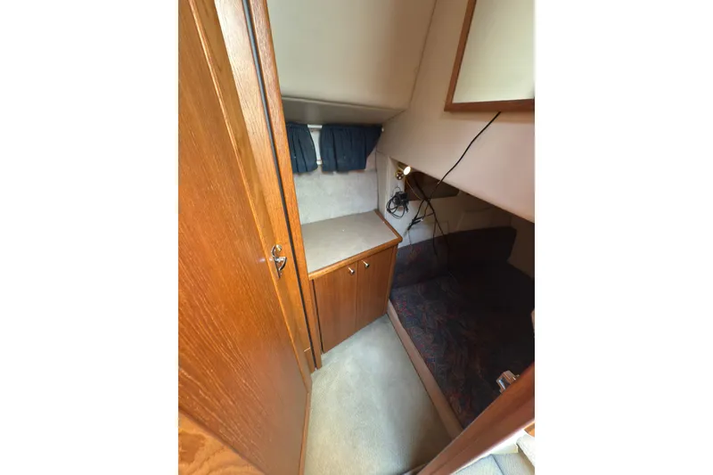 Slide: The Image of 1997 Bayliner 3788 Command Bridge Motoryacht cabin interior with wood cabinetry and cozy sleeping area. - 29