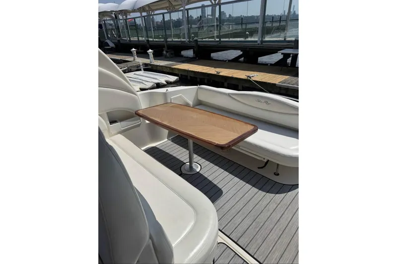 Slide: The Image of 2003 Sea Ray 360 Sundancer boat interior with wooden table and white seating. - 3