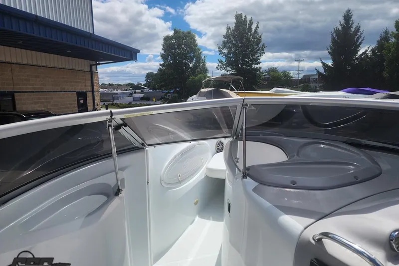 Slide: The Image of 2005 Baja 242 Islander boat interior with windshield, docked outdoors under cloudy sky. - 37
