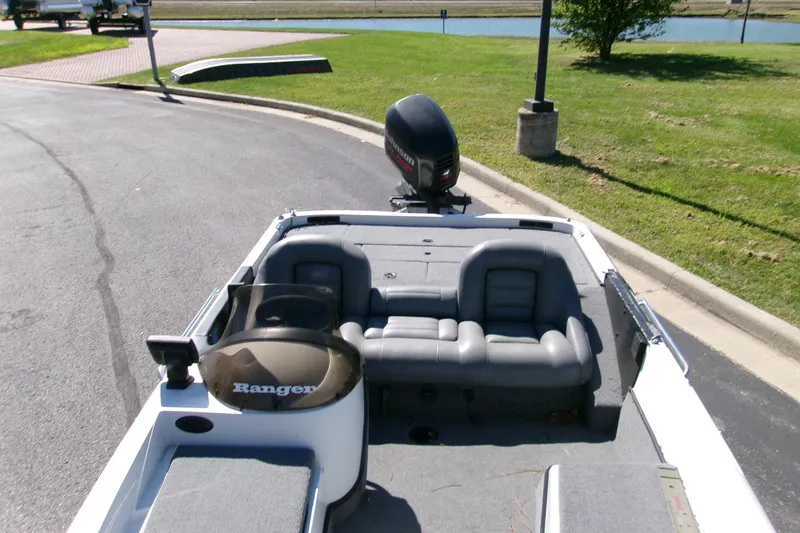Slide: The Image of 1998 Ranger 461 VS Commanche boat with seating and motor, parked near a grassy area. - 3