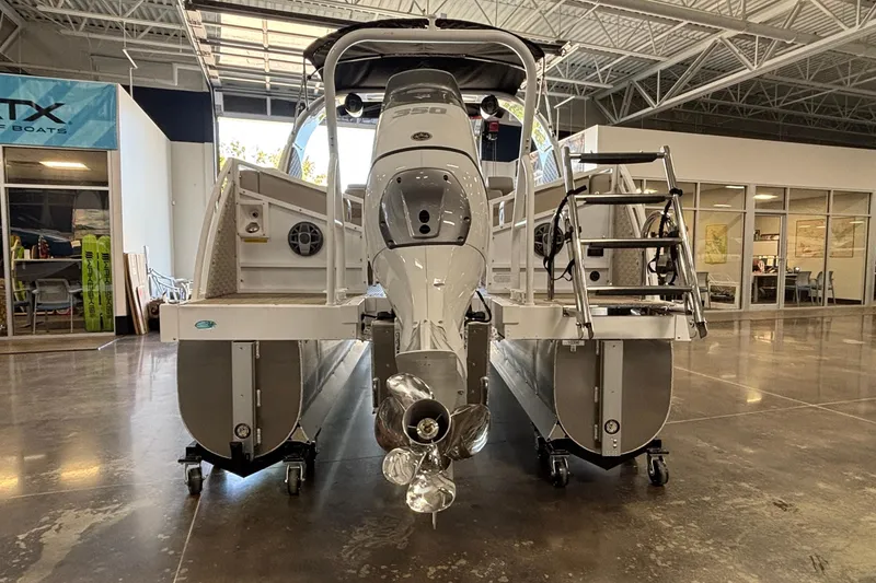 Slide: The Image of 2026 JC Sporttoon 26TT pontoon boat in showroom, rear view with motor and ladder. - 7