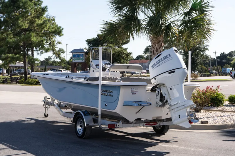 Slide: The Image of 2026 Carolina Skiff 21 LS boat with Suzuki outboard motor on trailer, parked near palm trees. - 3