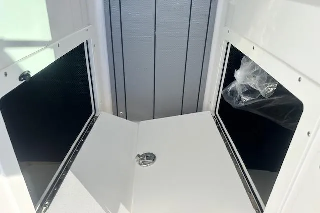 Slide: The Image of 2026 Chaparral 21 SSi boat storage compartments with open doors and latch. - 16
