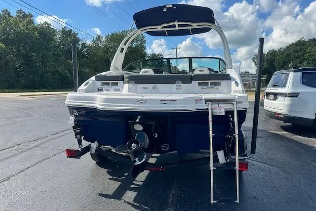 Slide: The Image of 2026 Chaparral 21 SSi boat, rear view, parked on pavement under a blue sky. - 2