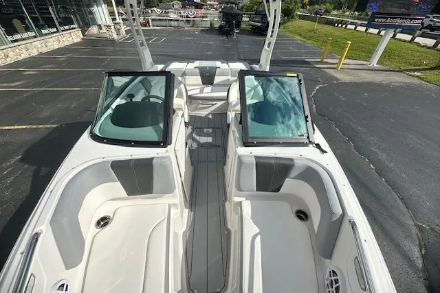Slide: The Image of 2026 Chaparral 21 SSi boat interior with dual windshields and seating, parked outdoors. - 22