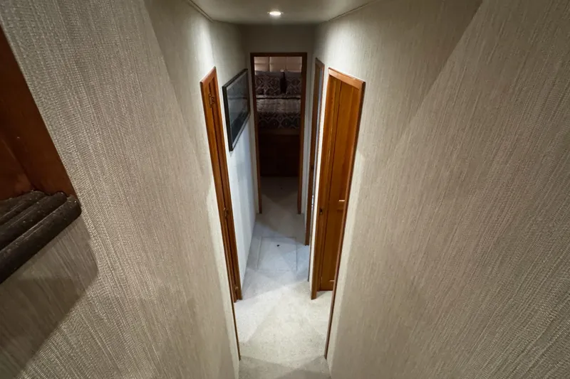 Slide: The Image of Narrow hallway inside 2002 Cavileer 48 Flybridge Sportfish yacht with wooden doors and carpeted floor. - 13