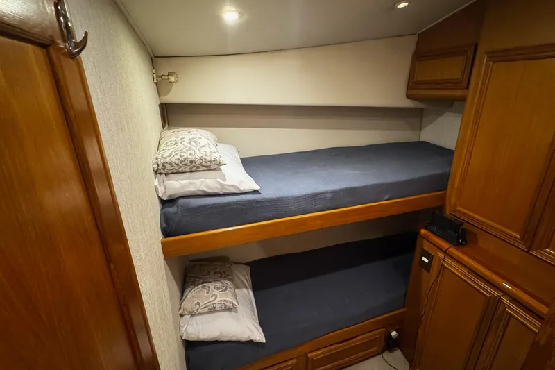 Slide: The Image of Interior of 2002 Cavileer 48 Flybridge Sportfish with cozy bunk beds and wooden cabinetry. - 18