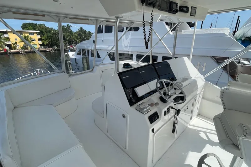 Slide: The Image of 2002 Cavileer 48 Flybridge Sportfish helm with modern controls and seating, docked by waterfront. - 40