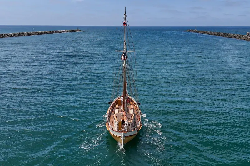 Slide: The Image of 1938 Norwegian Double Ended Ketch sailing through a calm blue sea channel. - 17