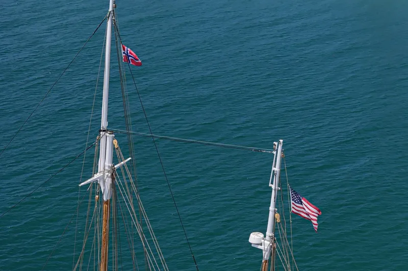 Slide: The Image of Masts of 1938 Norwegian Double Ended Ketch with flags over blue sea. - 19