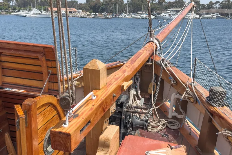 Slide: The Image of 1938 Norwegian Double Ended Ketch deck with wooden details and rigging, docked in marina. - 25