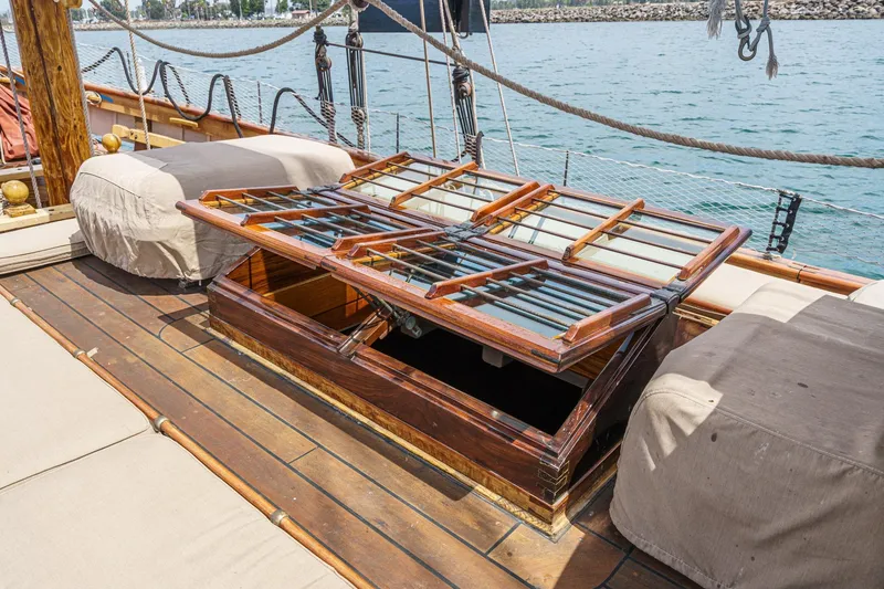 Slide: The Image of 1938 Norwegian Double Ended Ketch deck with open wooden hatch, near calm waters. - 39