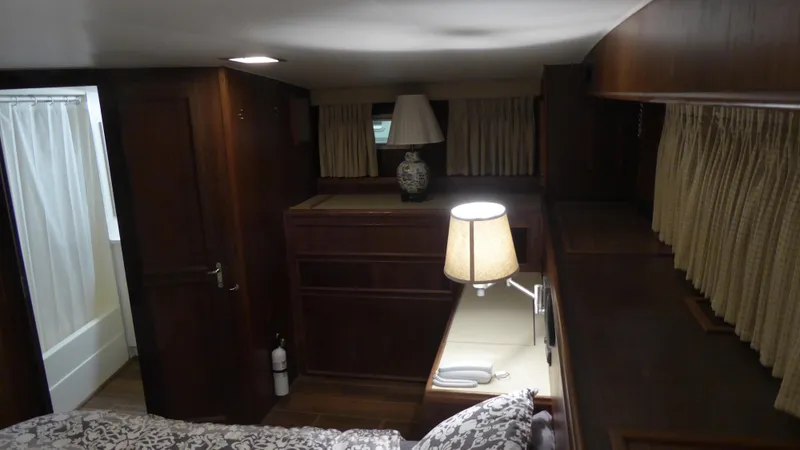 Slide: The Image of 1985 Hatteras 56 Motor Yacht interior with wood paneling, bed, and lamps. - 25