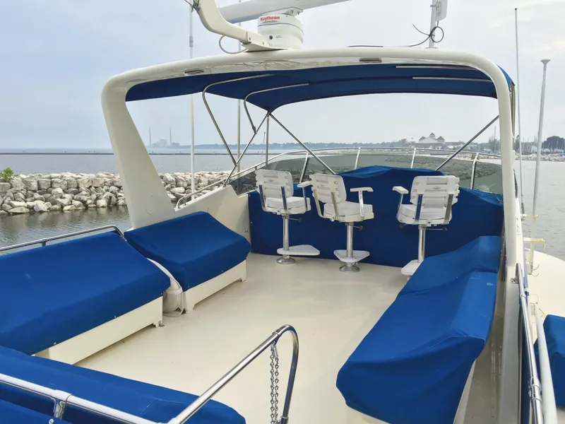 Slide: The Image of 1985 Hatteras 56 Motor Yacht deck with blue seating and scenic waterfront view. - 3