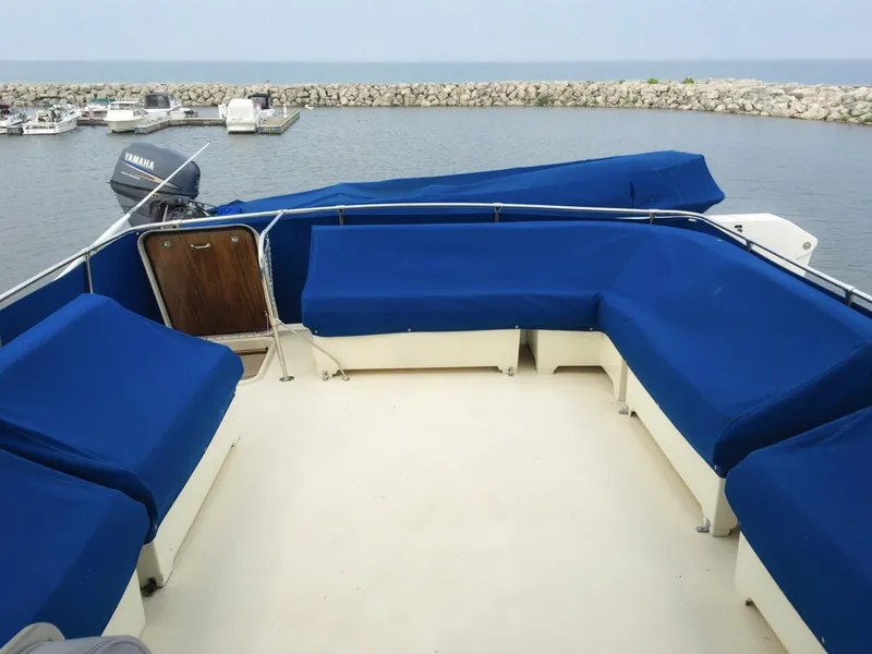 Slide: The Image of 1985 Hatteras 56 Motor Yacht with blue cushioned seating on deck, docked at marina. - 30