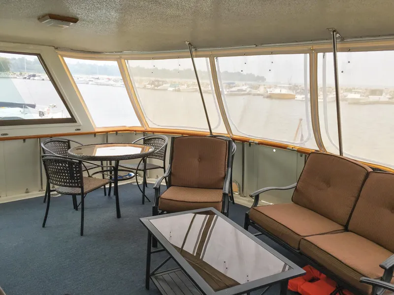 Slide: The Image of 1985 Hatteras 56 Motor Yacht interior with seating and table, overlooking marina. - 6