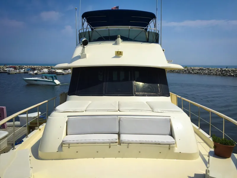Slide: The Image of 1985 Hatteras 56 Motor Yacht docked in a marina, featuring spacious deck seating. - 9