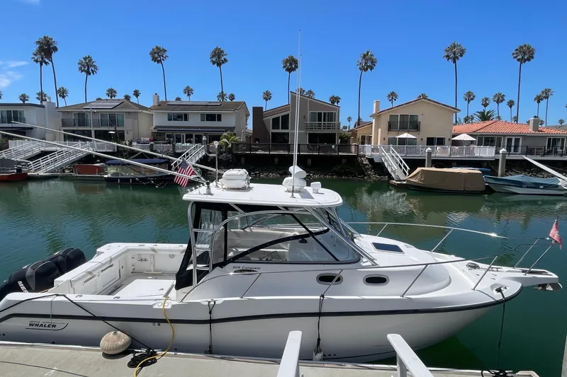 The Image of 2004 Boston Whaler 305 Conquest docked in a scenic marina with palm trees. - 0