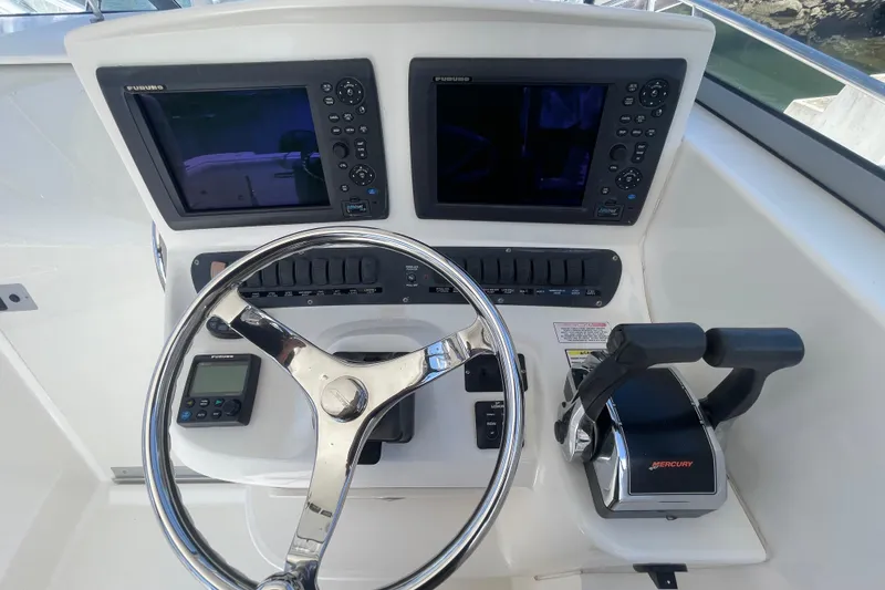 Slide: The Image of Control panel of a 2004 Boston Whaler 305 Conquest boat with steering wheel and navigation screens. - 16
