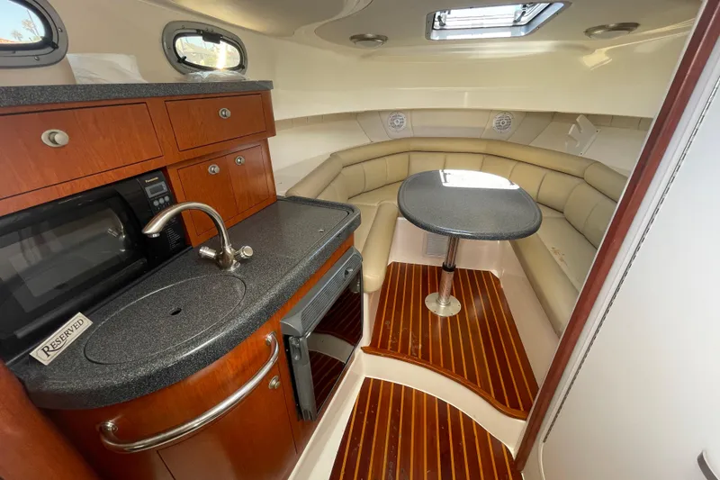 Slide: The Image of 2004 Boston Whaler 305 Conquest cabin interior with kitchenette and seating area. - 18