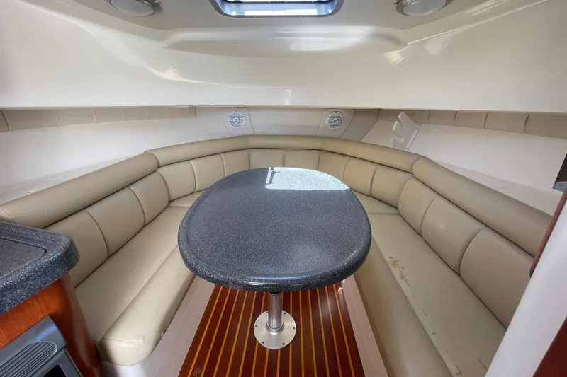 Slide: The Image of 2004 Boston Whaler 305 Conquest cabin with beige seating and oval table. - 19