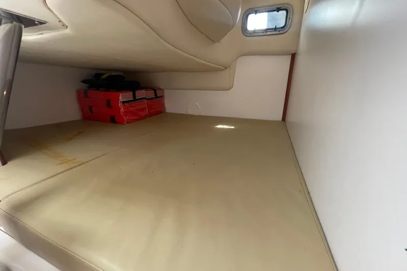 Slide: The Image of 2004 Boston Whaler 305 Conquest cabin interior with beige cushions and storage space. - 22